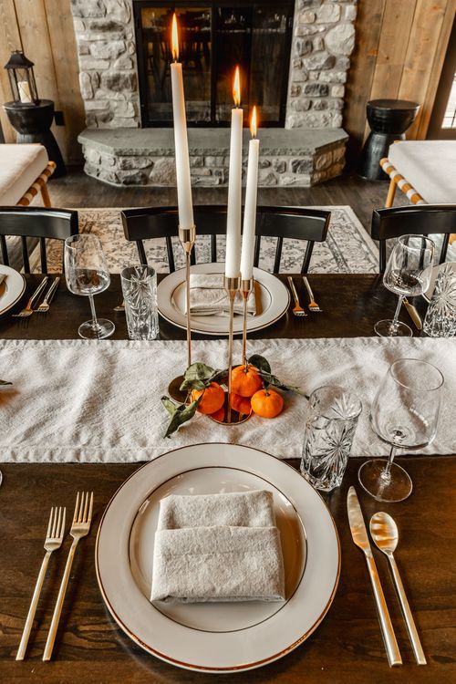 Formal place setting with tall lit candles and a stone fireplace glowing in the background