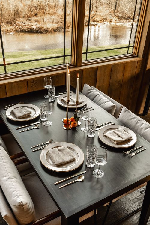 Table set for four beside a window framing a creek and green lawn