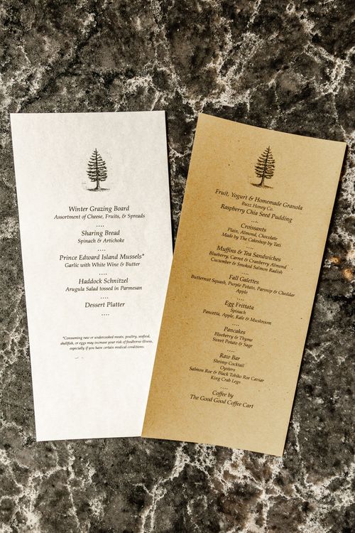 Two cream and kraft-paper menu cards laid on a dark marble surface