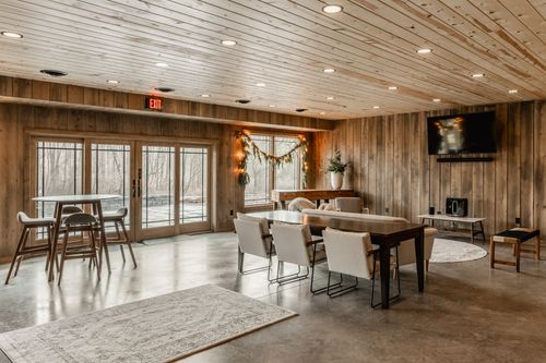 Wood-paneled lounge with high-top tables, a wall-mounted TV and glass doors to the patio