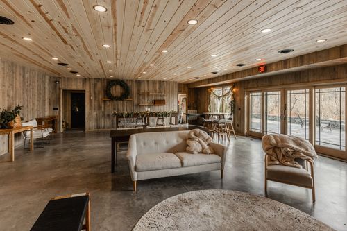 Open lounge with a cream sofa, wood bench and shelving decorated with a pine wreath