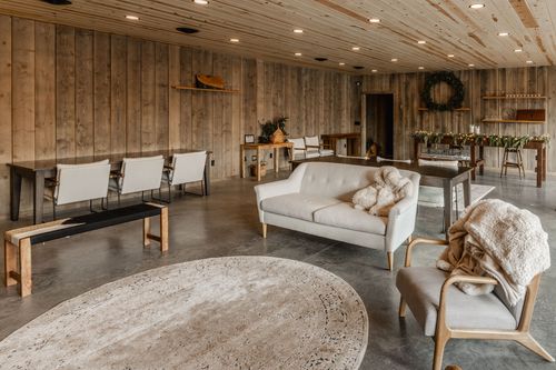 Living area with a loveseat, accent chairs and rustic wood shelving under a wreath
