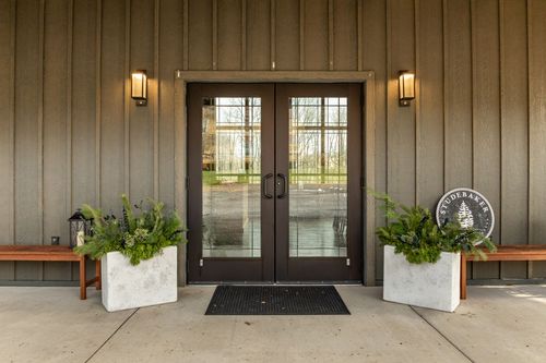 Symmetrical entry with double doors, wall sconces and potted greenery in planters