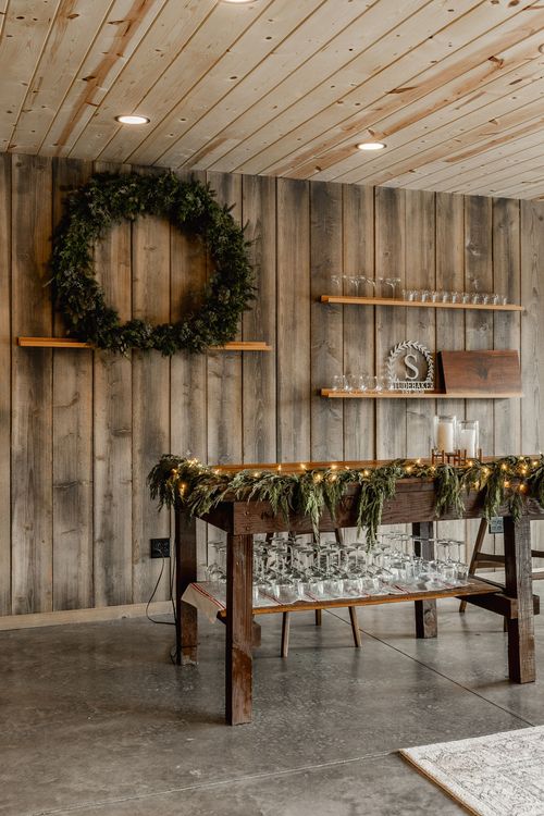 Wood serving table wrapped in lit garland with glassware displayed underneath