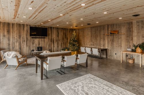 Gathering room with a wall-mounted TV, lit Christmas tree and cushioned chairs