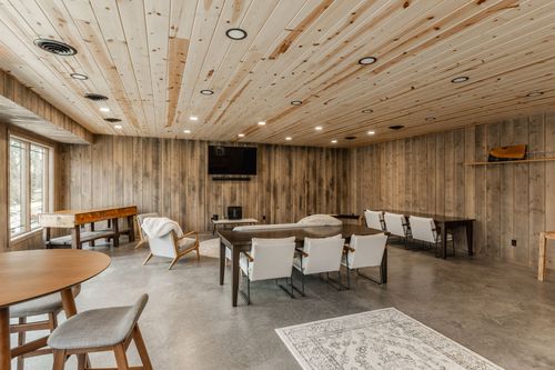 Rustic room with a garland-wrapped window, wood bench seating and a mounted television
