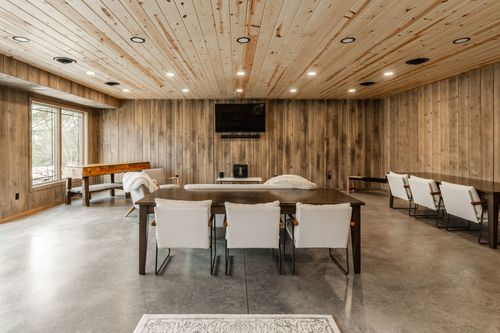 Reception room with rows of tables and benches beneath a raw wood ceiling