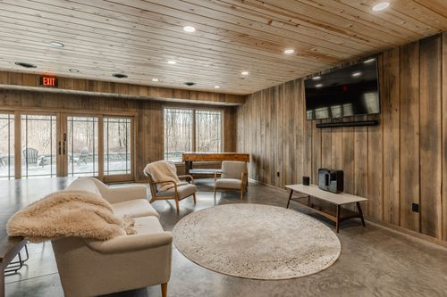 Cozy lounge with a cream sofa, sherpa throw and a glimpse of a piano through French doors