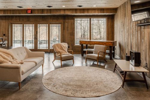 Living room with a cream sofa and armchairs beneath an exit sign and glass doors