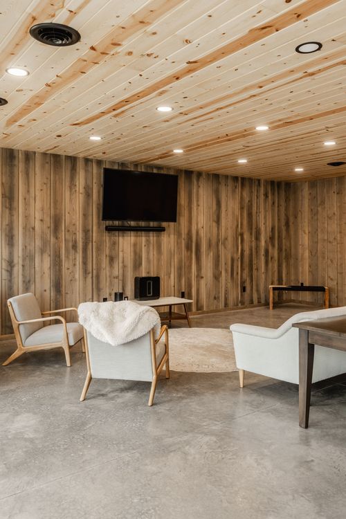 Open living area with polished concrete floors, a mounted TV and mid-century chairs
