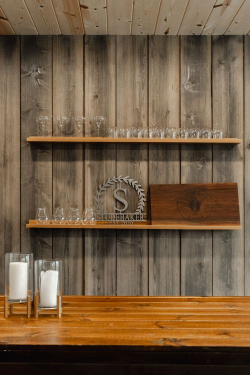 Open shelving displaying a framed barn photograph, stemware and a wood serving table