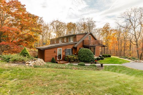Two-story log home exterior with an upper deck and stone-edged walkway