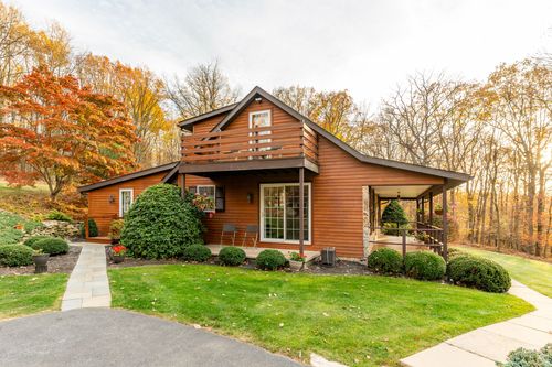 Log home exterior with a glass sunroom addition and covered deck seating