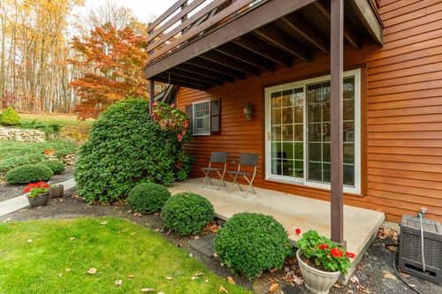Covered deck with patio chairs, potted plants and a sliding glass door