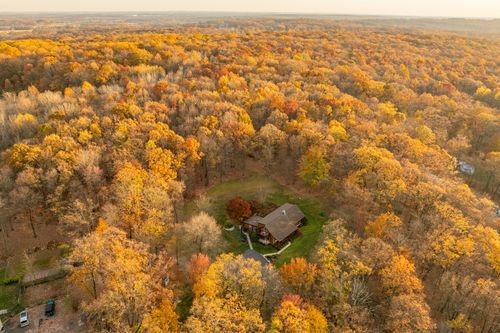 Aerial view of a home nestled deep within a dense autumn forest