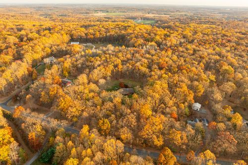 Aerial view of a rural wooded property surrounded by golden fall canopy