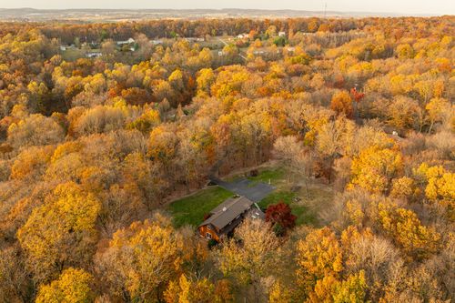 Aerial view of a rural wooded property with distant hills and farmland