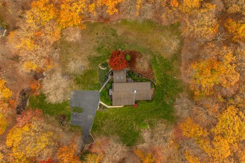 Overhead aerial view of a home's roofline, driveway and surrounding fall foliage