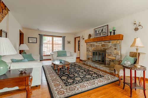 Living room with white sofas, a stone fireplace and teal accent pillows
