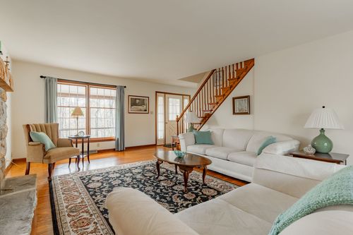 Living room with a white sectional sofa, wood staircase and patterned area rug