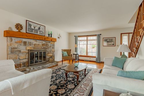 Living room with a stone fireplace, wood mantel and white upholstered seating
