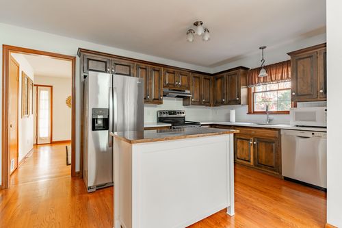 Open kitchen with dark wood cabinetry, stainless appliances and a butcher block island
