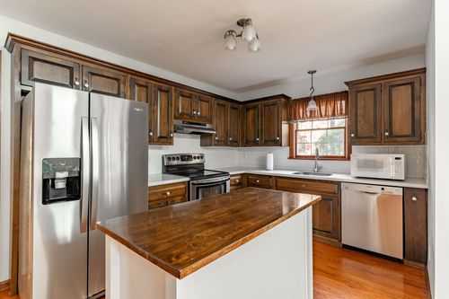 Kitchen with dark wood cabinets, a pendant light and a gas range