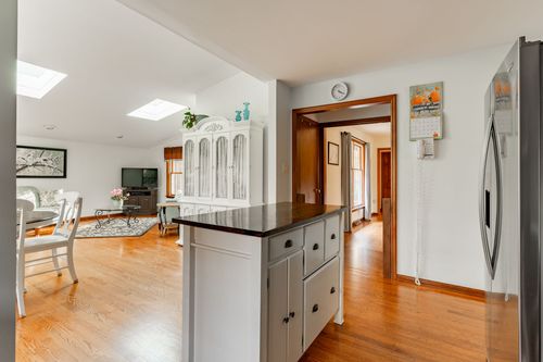 Open dining and living area with skylights and a white glass-front china cabinet
