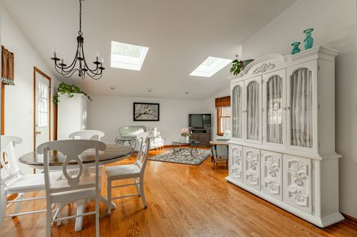 Sunroom sitting area with pale blue sofas, skylights and a mounted TV