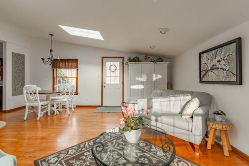 Open living and dining area with skylights, a round table and hardwood floors