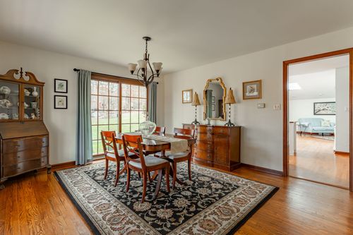 Traditional dining room with a wrought-iron chandelier, curtained windows and a wood table