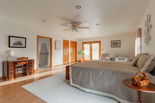 Bedroom with a stone accent wall, ceiling fan and a row of wood paneled doors