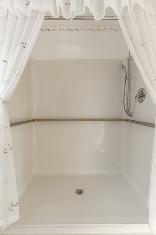 Curtained walk-in shower stall with a handheld shower head