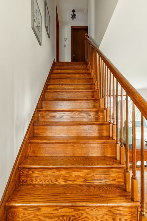 Oak staircase with a turned wood railing leading to an upper hallway