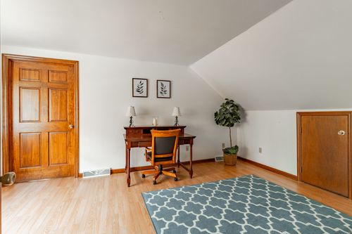 Bonus room with a writing desk, sloped ceiling and a blue trellis-pattern rug