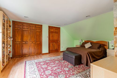 Bedroom with sage green walls, wood paneled closets and a red patterned rug