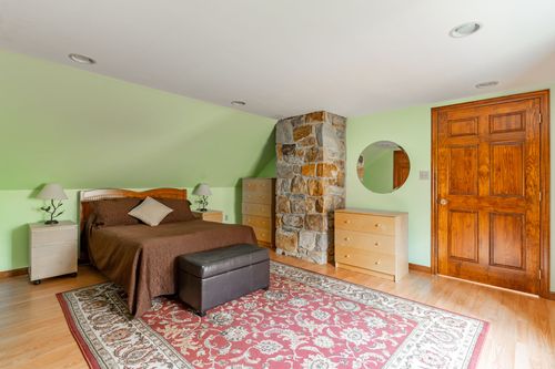 Bedroom with sage green walls, a stone chimney accent and brown bedding