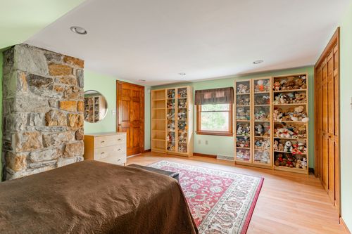 Bedroom with built-in glass display shelving for collectibles and a red floral rug