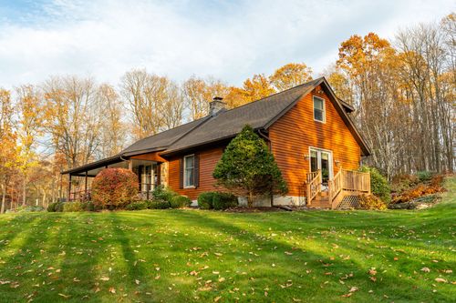 Side exterior of a log-style home with cedar siding and a small covered entry deck