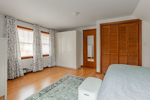 Bedroom with floral drapes, built-in white cabinetry and wood closet doors