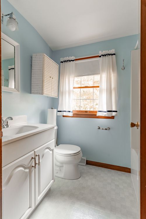 Bathroom with pale blue walls, a wicker wall cabinet and white vanity