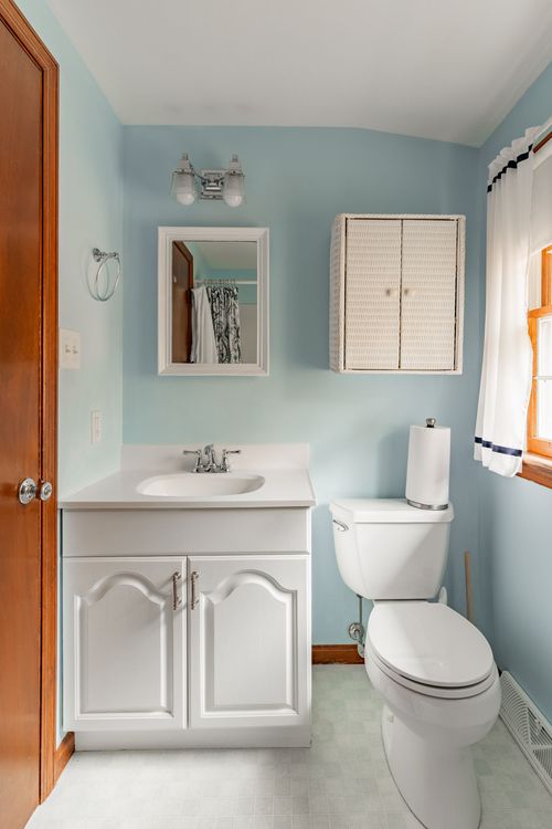 Bathroom with light blue walls, a framed mirror and white pedestal-style vanity