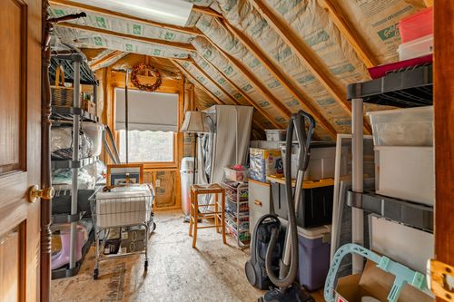 Unfinished attic storage space with exposed wood beams and metal shelving