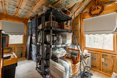 Attic storage room with plastic shelving, storage bins and a small wreath