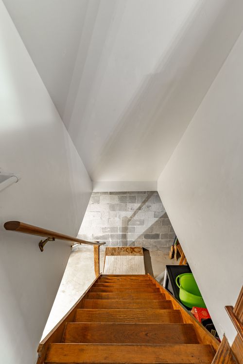Staircase descending to a basement with a cinder block wall and wood handrail