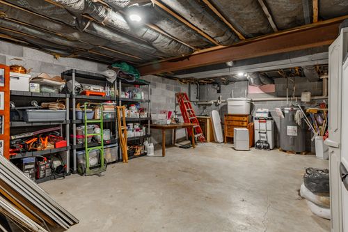 Unfinished basement with storage shelving, a workbench and mechanical equipment