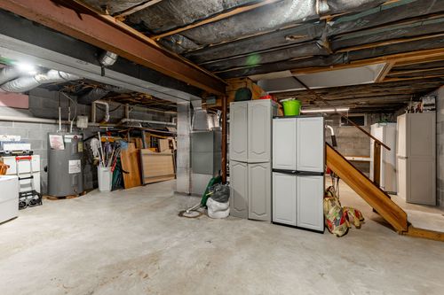 Basement storage area with plastic cabinets, shelving and a water heater