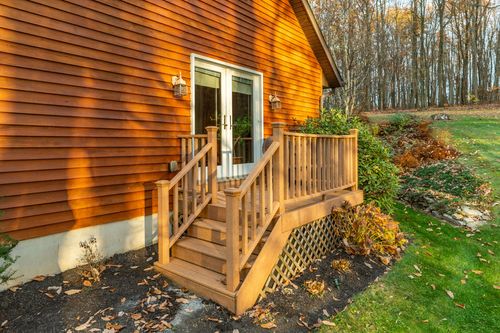 Wood deck with French doors and a side staircase leading to a landscaped yard