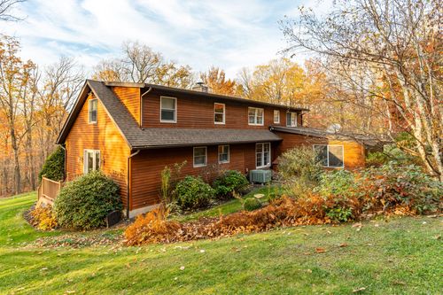 Rear exterior of a multi-gable log home with a sunroom addition and deck