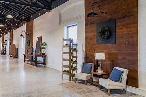 Hallway with a reclaimed wood accent wall, wreath, ladder planter, and lounge seating under arched windows